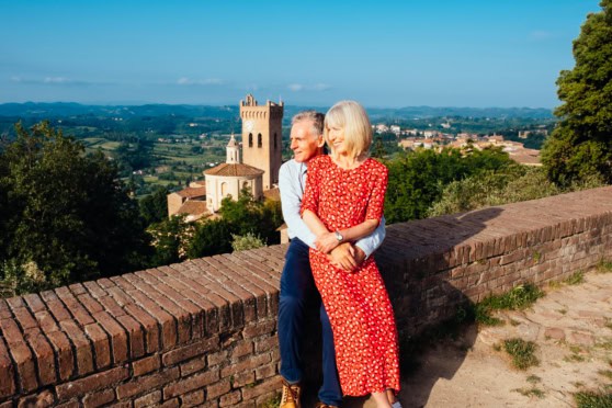 Senior couple enjoying scenic view of Italy's countryside from a historic terrace, highlighting the appeal of retiring abroad in Italy.