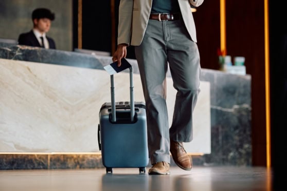 Close up of man with passport and suitcase in a hotel lobby, indicating expat repatriation