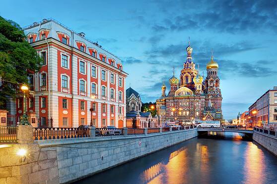 Scenic view of Saint Basil's Cathedral and colorful buildings along the Moskva River in Moscow at dusk.