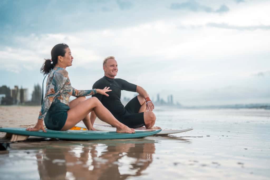 Expat couple practicing yoga on the beach in Australia, enjoying the coastal scenery and lifestyle.