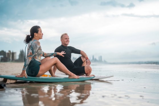 Expat couple practicing yoga on the beach in Australia, enjoying the coastal scenery and lifestyle.