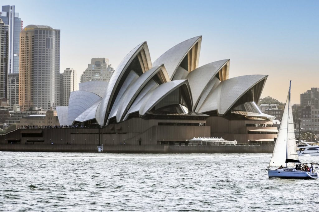 Iconic Sydney Opera House with modern city skyline in the background, showcasing Australia's famous architectural landmark and vibrant urban environment.