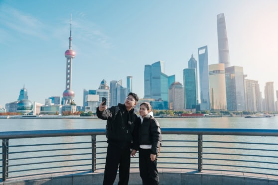 Shanghai skyline with iconic skyscrapers and a couple taking a selfie.