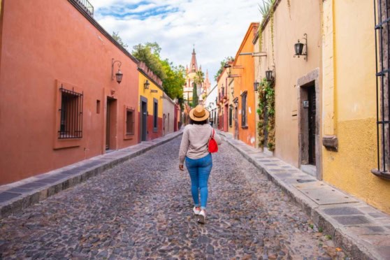 Woman walking on colorful cobblestone street in Mexico, exploring vibrant local architecture during her move from the US to Mexico.