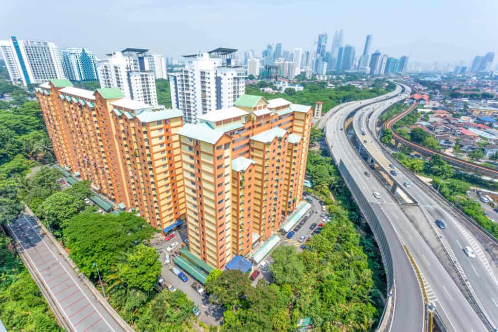 A vibrant cityscape in Malaysia featuring high-rise residential buildings and extensive highway infrastructure, ideal for retirees seeking a comfortable and accessible lifestyle.