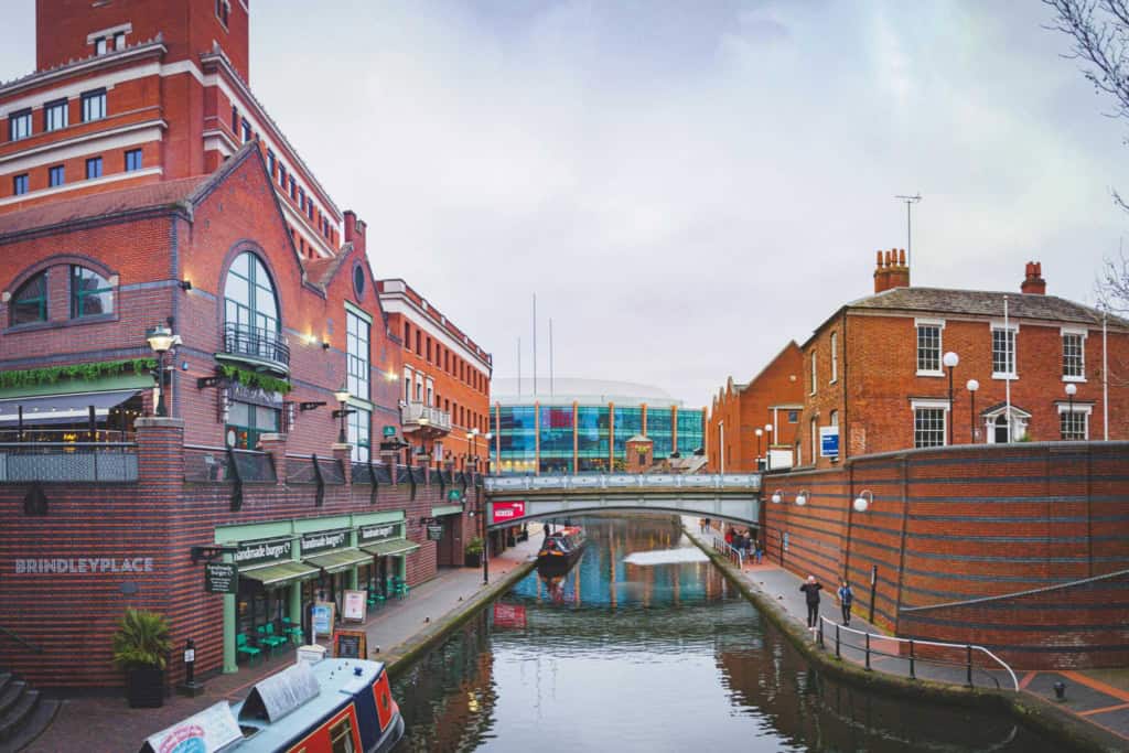 A scenic view of the historic city center in the UK, featuring red brick buildings, a canal, and modern structures, ideal for retirees considering relocating to the UK.