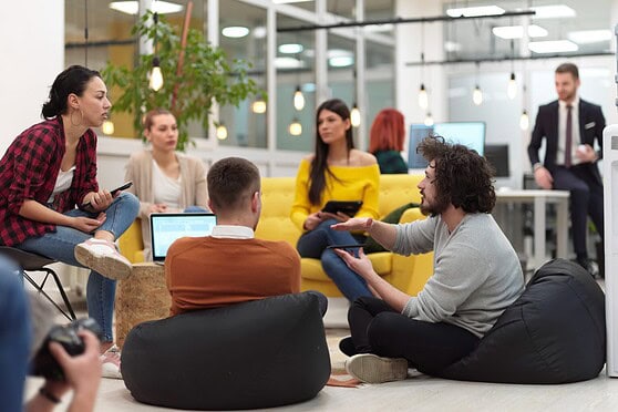 Diverse group of young professionals engaging in a discussion in a modern office setting, promoting international insurance services for global citizens.
