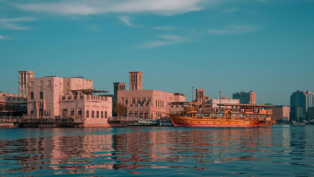 View of Dubai waterfront with traditional boat and modern buildings, representing international travel and insurance services for global citizens.
