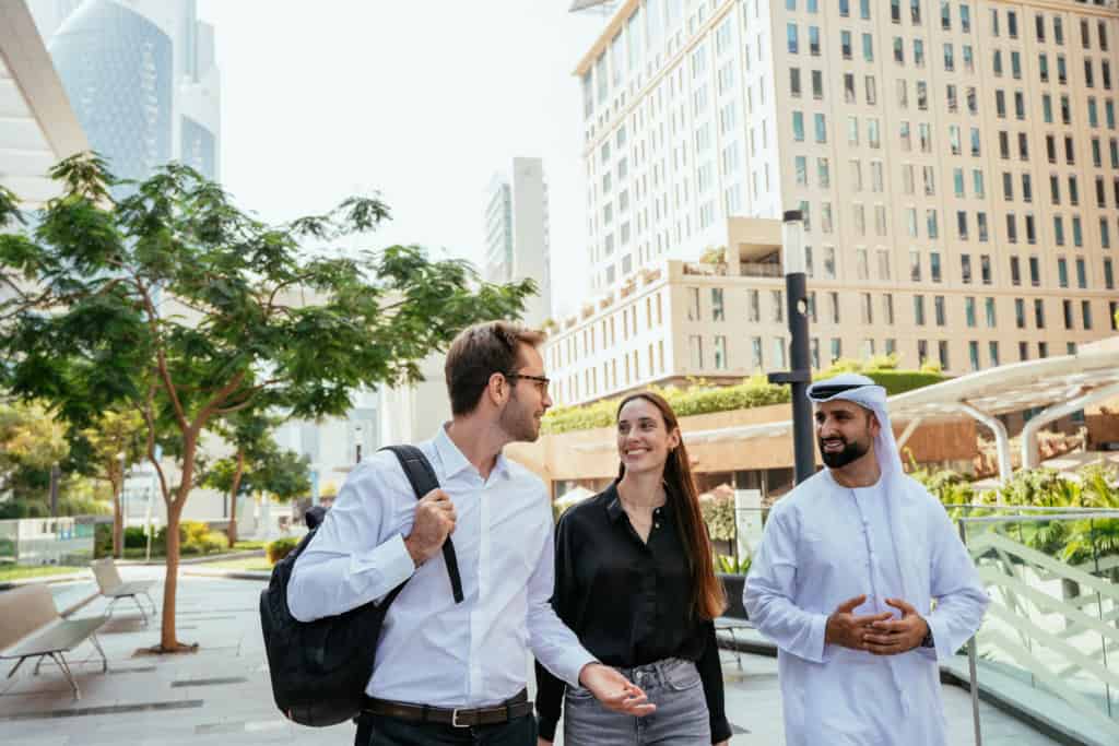 Business travelers engaging in conversation outdoors in a modern cityscape, representing international insurance services for global citizens and expatriates.
