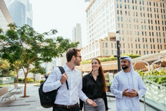 Business travelers engaging in conversation outdoors in a modern cityscape, representing international insurance services for global citizens and expatriates.