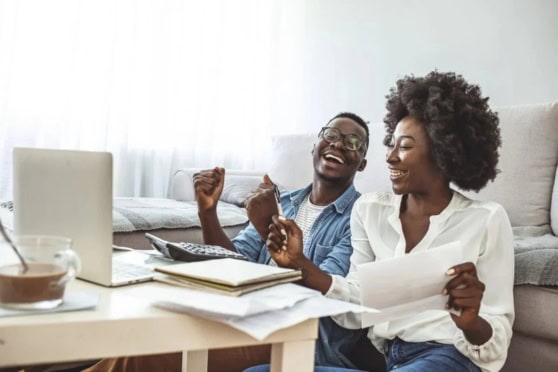 Expats discussing financial advice at home, with documents and laptop, emphasizing international insurance solutions for global citizens.