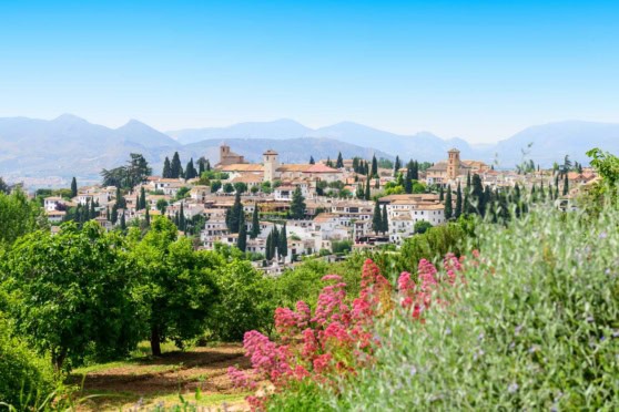 An image of a picturesque mountain village in Spain, surrounded by lush greenery and colorful flowers, ideal for retirees seeking a peaceful and beautiful place to settle.