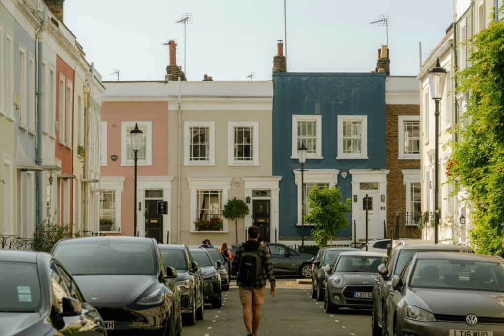 An image of a charming street in the UK with colorful houses and parked cars, illustrating the appeal of retiring in the UK.