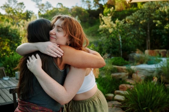 Two women embracing outdoors, symbolizing support and reunion for expats returning home after living abroad.