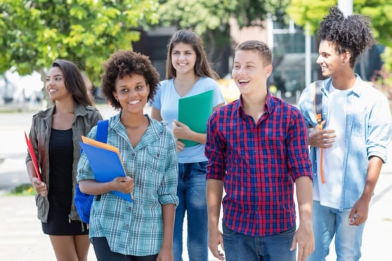 International students walking together with backpacks and books on a university campus.