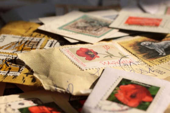 Postcards and letters from international travelers and expatriates, featuring colorful stamps and handwritten messages, emphasizing global communication and insurance services for international citize.