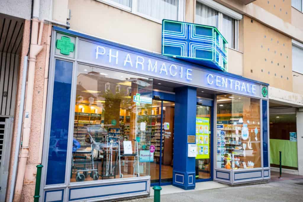Exterior of a pharmacy in France with green pharmacy cross signs