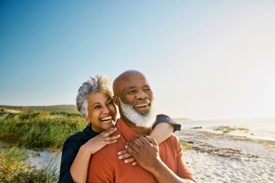 Smiling senior couple enjoying a day at the beach, representing international health insurance coverage for global citizens.