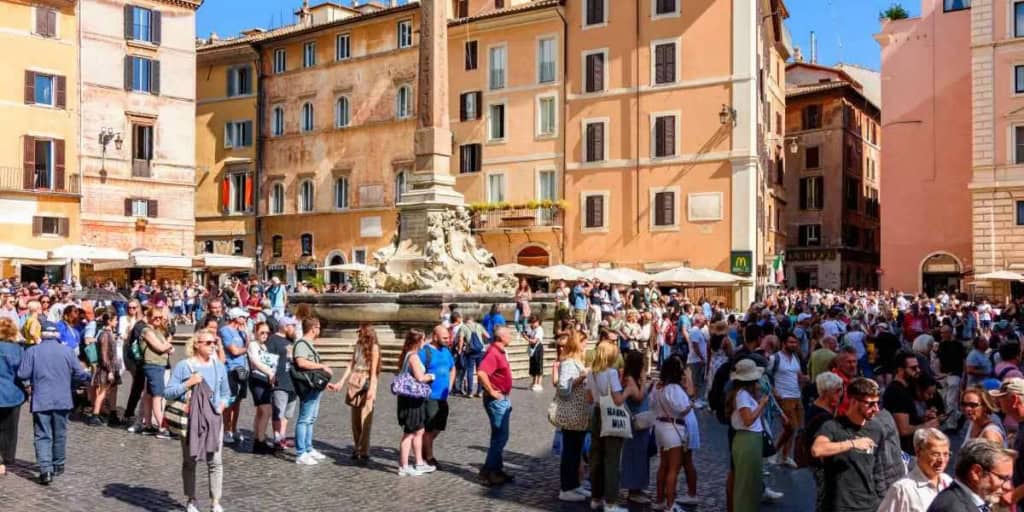 Crowd of tourists in a historic square in Rome, which has one of the highest cost of living in Italy
