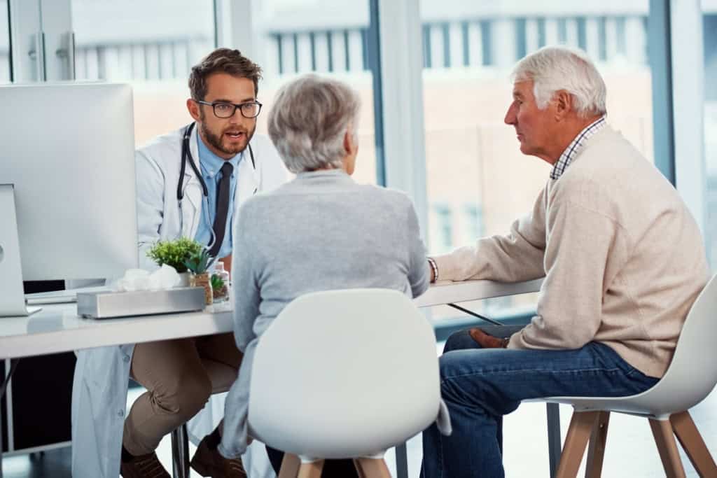 Medical consultation between a doctor and elderly couple in an office setting, discussing health insurance options for international citizens; an important part of retirement planning for expats