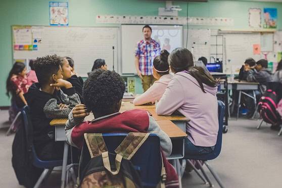 Diverse classroom with students and teacher engaging in a lesson, promoting inclusive education for international citizens.