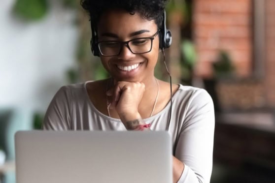 Smiling woman with headset using a laptop for international insurance support, representing customer service for global clients.