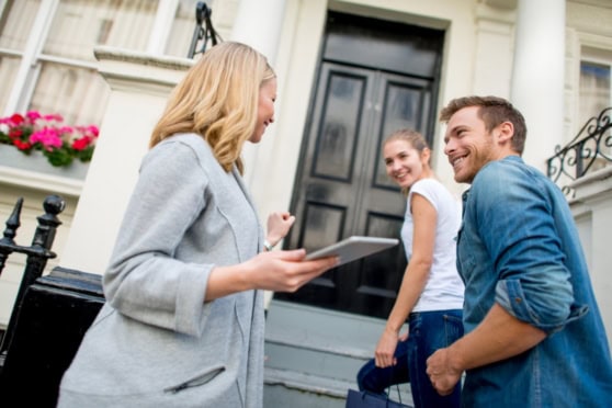 Real estate agent discussing property details with a couple outside a stylish home, highlighting international property investments.