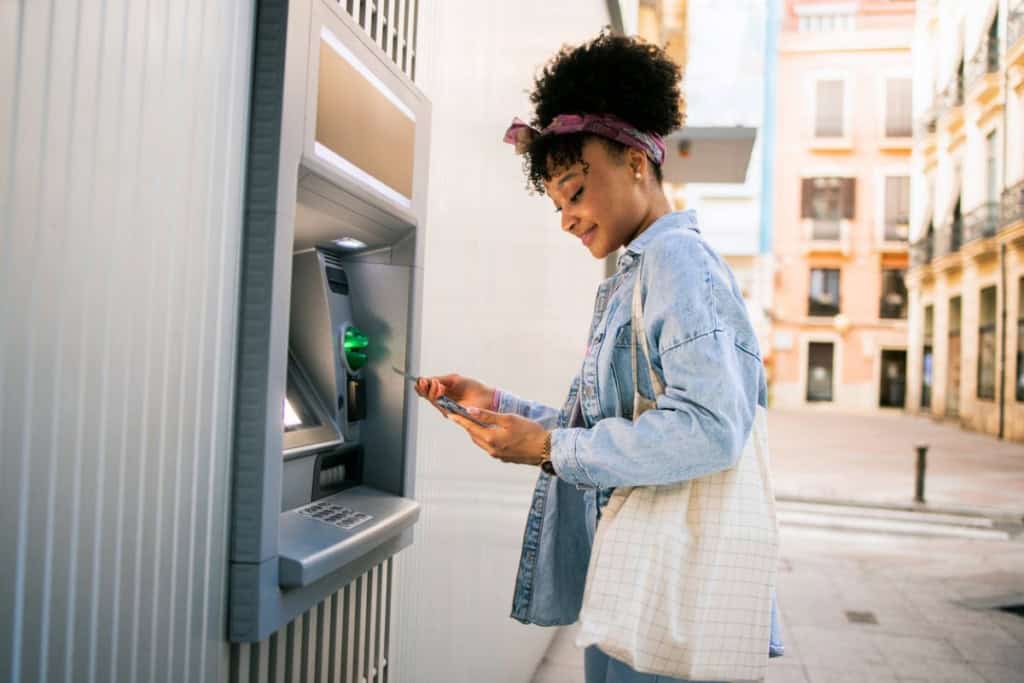 Woman using an ATM on the street, highlighting international banking options for expatriates.