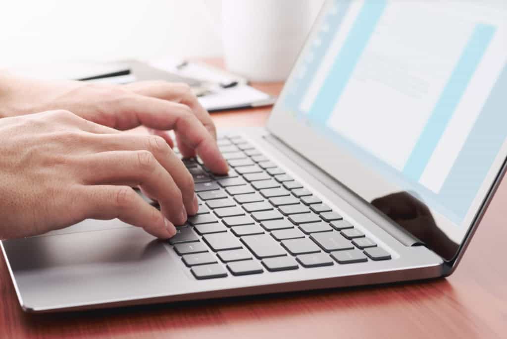 Close-up of hands typing on a laptop keyboard, representing international insurance services and online documentation.
