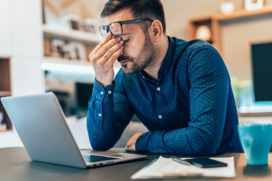 a man looking stressed working from home on his laptop, indicating the issue of remote work burnout