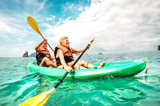A happy senior couple enjoying retiring in the Philippines, sitting in a kayak on clear, calm ocean waters.