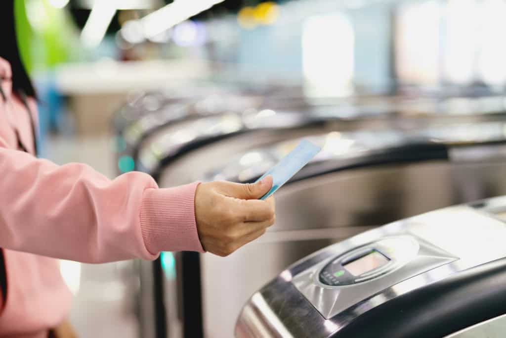 Person holding a boarding pass near a self-check-in machine at an airport, illustrating daily living costs when moving abroad