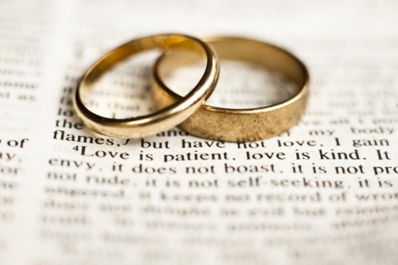 Two gold wedding bands resting on a page of a book, representing love, marriage, and lifelong commitment.