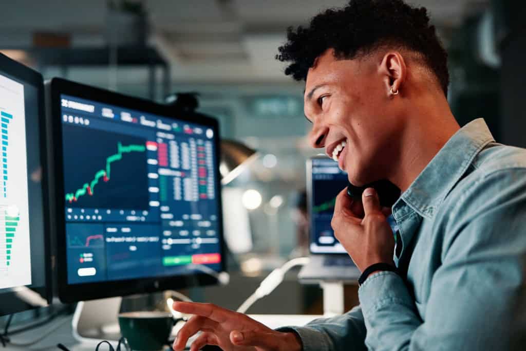a fintech worker consulting a client while looking at data on a monitor showing the rise of international remote jobs in finance