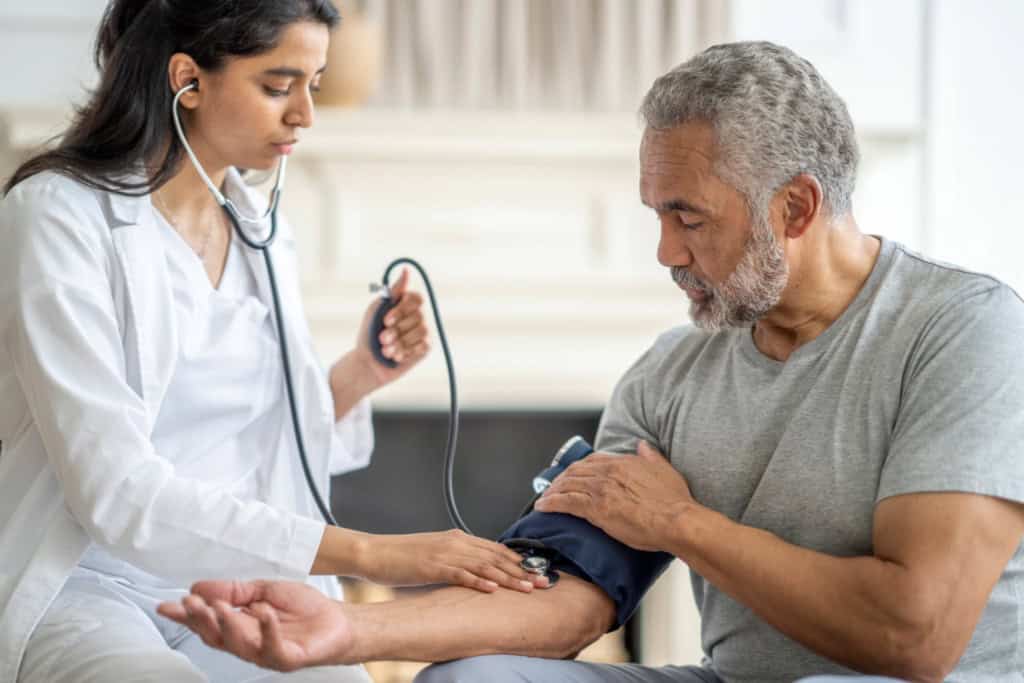 A doctor checks a patient’s blood pressure, an example of care that may appear in their medical history.