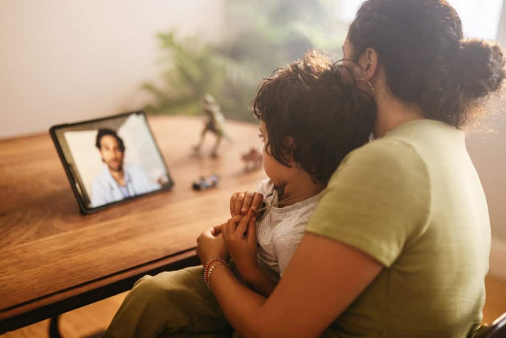 A parent and child speaking with a doctor online, showing how telemedicine can help families access healthcare while living abroad.