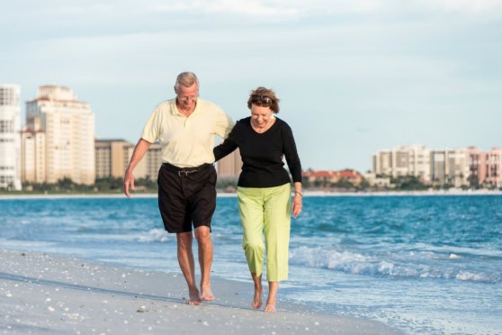 Senior couple walking along the beach and enjoying a relaxing lifestyle after retiring in the USA
