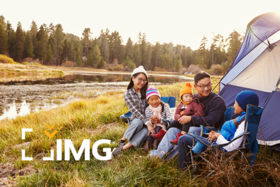 Family camping scene near a lake in a forested area, with children and parents enjoying outdoor activities in the countryside.