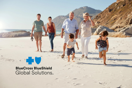 Family walking on beach in Spain with mountains in background, representing international travel and health insurance coverage.