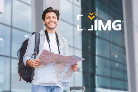 Young man with backpack and map at airport in front of IMG logo, international travel context.