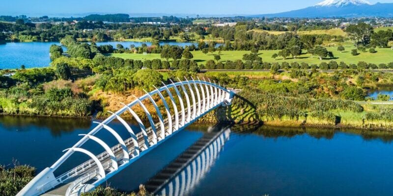 Aerial view on a beautiful bridge across a small stream with Mount Taranaki on the background. New Zealand Aerial view on a beautiful bridge across a small stream with Mount Taranaki on the background, New Zealand
