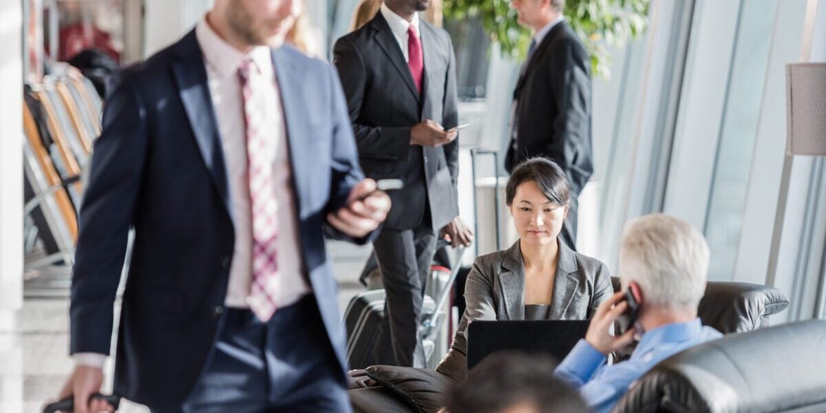 Business professionals in an airport lounge waiting for their flight, highlighting the importance of group travel insurance for corporate teams