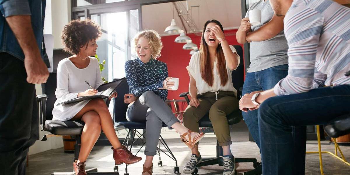 co-workers-laughing a group of colleagues sitting in a circle and chatting