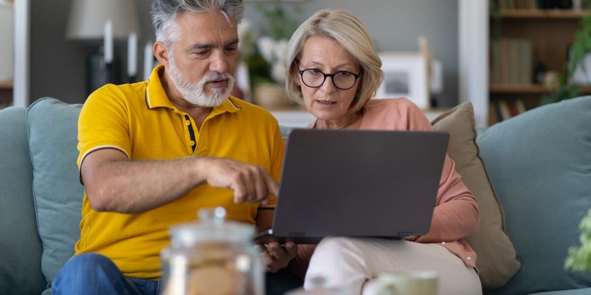 couple-researching-on-laptop Senior couple sitting on a sofa using their laptop to compare international insurance plans