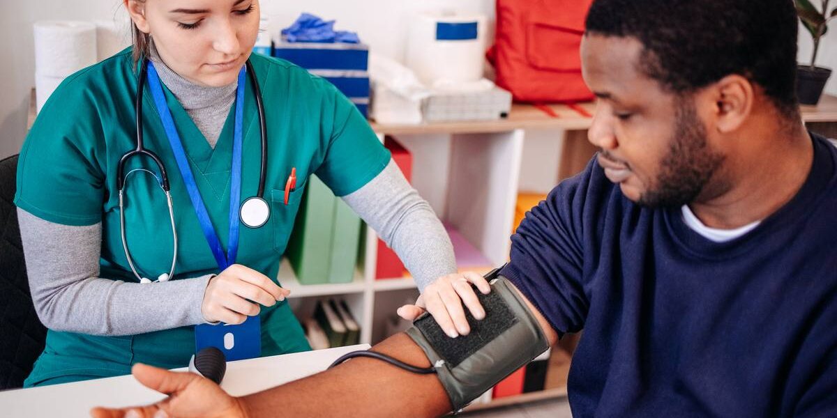 doctor-with-patient a medical assistant checking a young patient's blood pressure, indicating the importance of securing student group travel insurance for trip abroad
