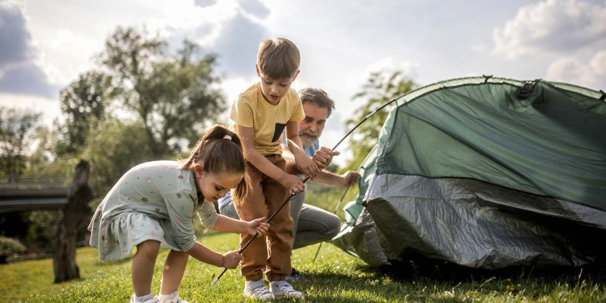 family-camping-vacation a family pitching a tent on a camping trip, one of the best family vacation ideas for 2025