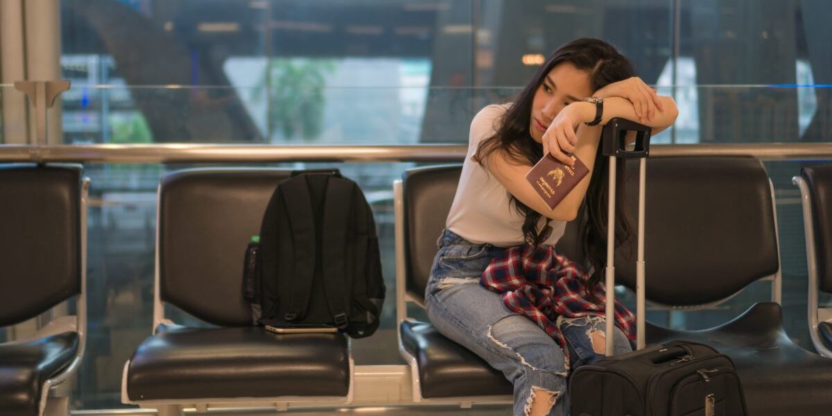 flight-delay-passenger a young girl waiting at an airport gate for her delayed flight, glad that she chose to purchase trip cancellation travel insurance