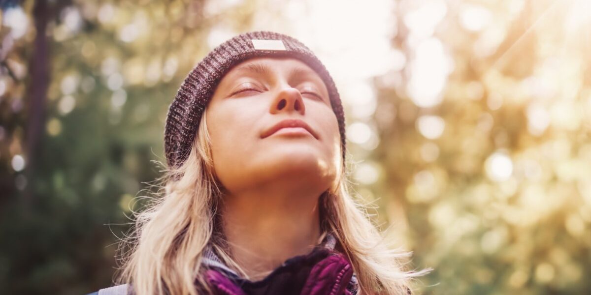 woman-in-nature a woman standing in a forest enjoying fresh air in one of the healthiest countries in the world