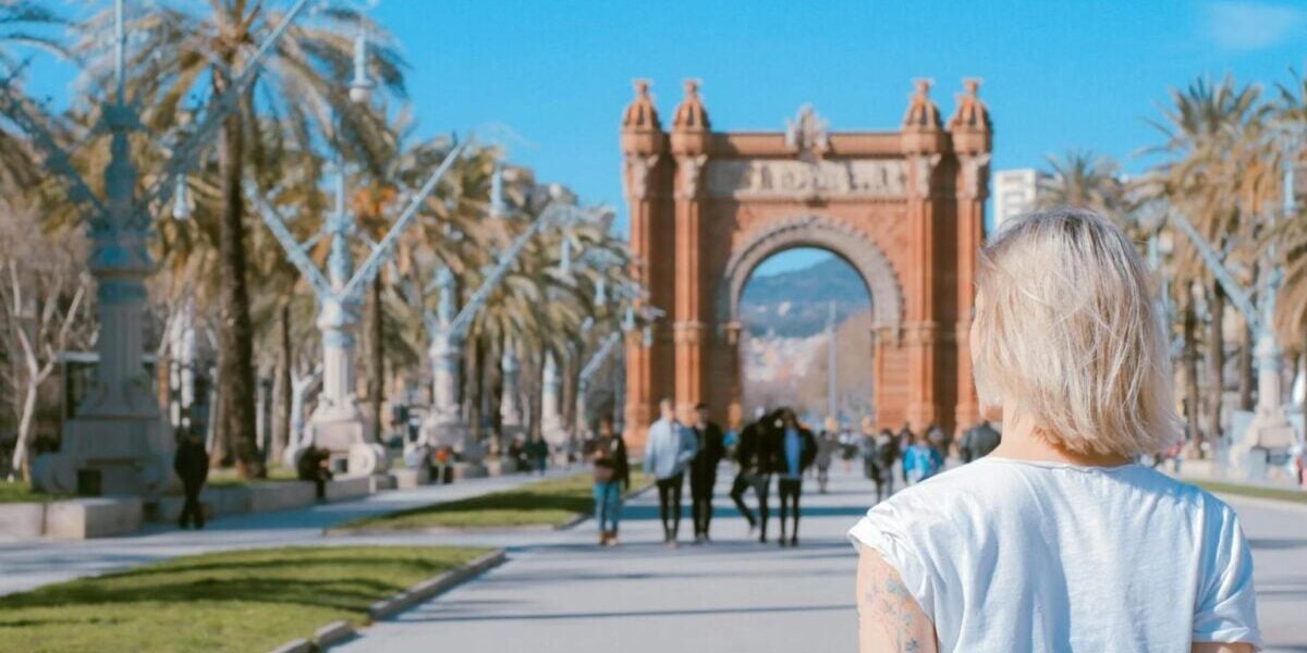 woman-walking-in-spain a woman standing in front of a landmark archway in Spain